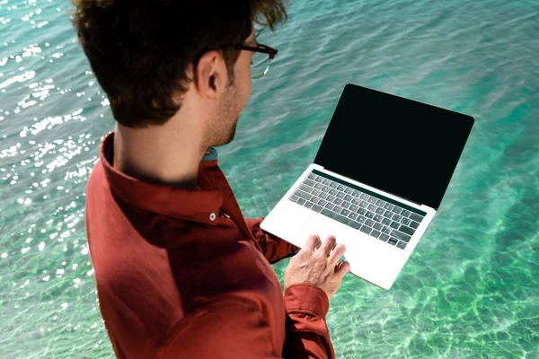Schöner Freiberufler mit Laptop im türkisfarbenen Wasser — Stockfoto