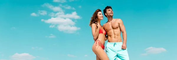 Smiling young couple together against blue sky with clouds, panoramic shot — Stock Photo