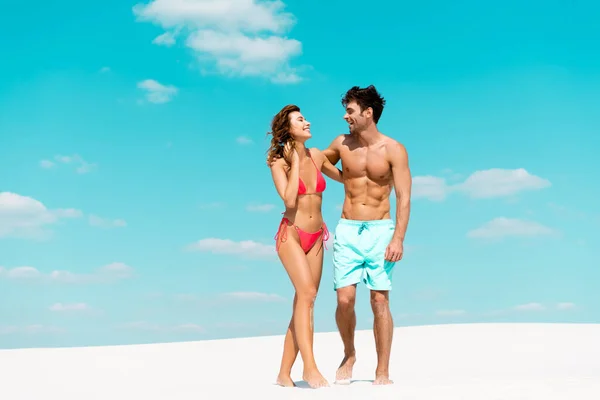 Усміхнена молода пара дивиться один на одного на піщаному пляжі — стокове фото