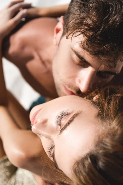 Vista aérea de pareja joven sexy apasionada besándose y abrazándose en la playa con los ojos cerrados - foto de stock