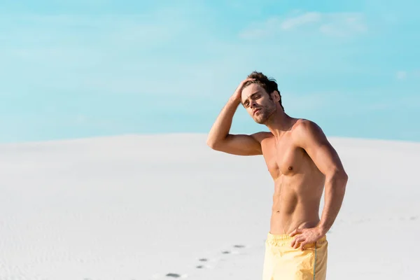 Uomo in pantaloncini da bagno con busto muscolare sulla spiaggia sabbiosa — Foto stock