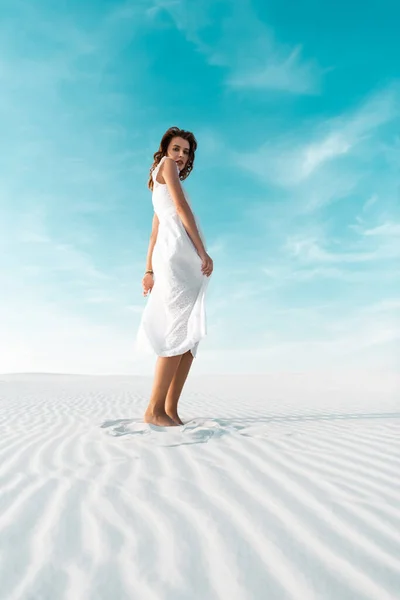 Beautiful girl in white dress on sandy beach with blue sky — Stock Photo