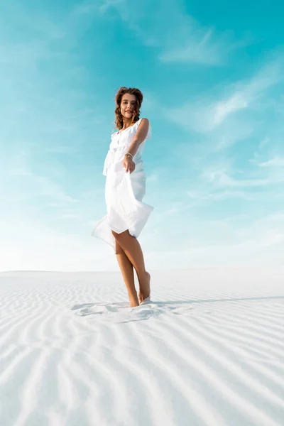 Hermosa chica en vestido blanco en la playa de arena con cielo azul - foto de stock