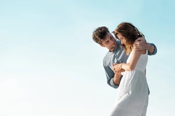 Jeune couple étreignant contre le ciel bleu — Photo de stock