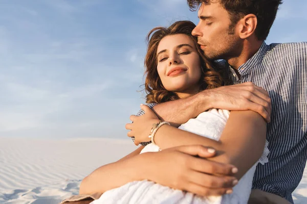 Улыбающаяся молодая пара обнимается на пляже — стоковое фото