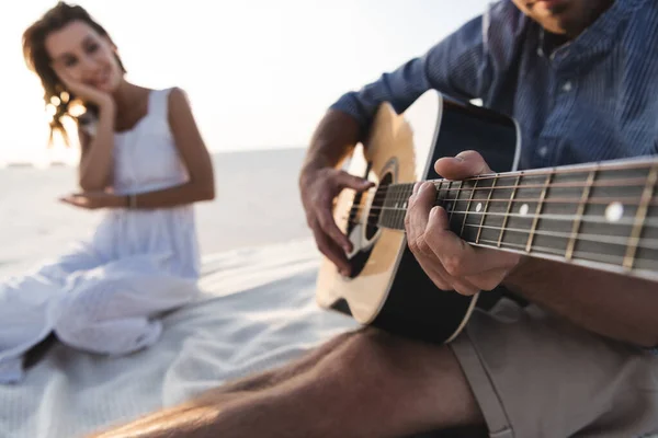 Messa a fuoco selettiva dell'uomo che suona la chitarra acustica alla fidanzata sulla spiaggia — Stock Photo