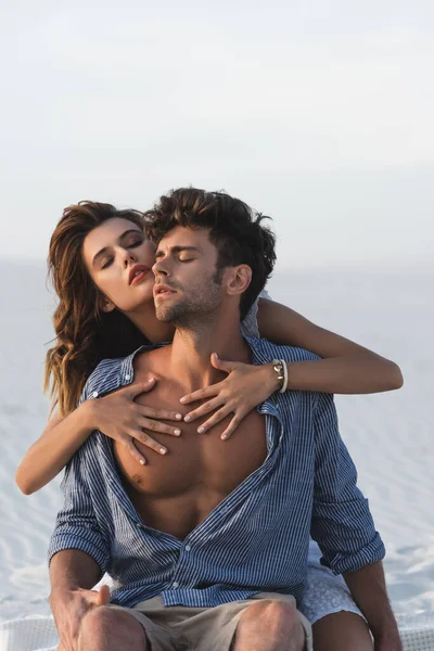 Apasionada joven tocando torso novio en la playa - foto de stock