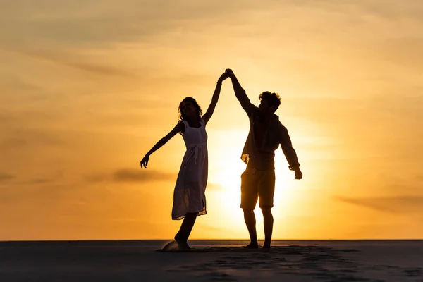 Silhouetten von Mann und Frau tanzen am Strand gegen die Sonne während des Sonnenuntergangs — Stockfoto