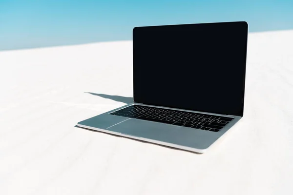 Laptop mit leerem Bildschirm am Sandstrand vor blauem Himmel — Stockfoto