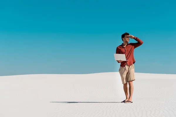 Jeune pigiste sur la plage de sable avec ordinateur portable contre ciel bleu clair — Photo de stock