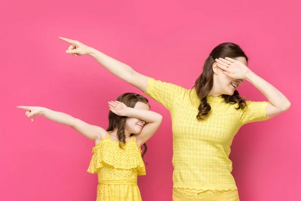 Joyeux mère et fille avec des visages obscurs pointant avec les doigts loin isolé sur rose — Photo de stock