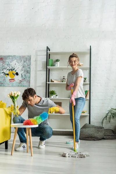 Homem feliz e mulher primavera limpeza na sala de estar — Fotografia de Stock