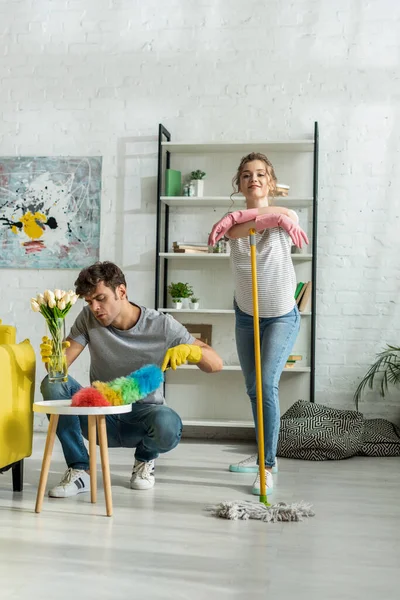 Handsome man and happy woman cleaning living room — Stock Photo