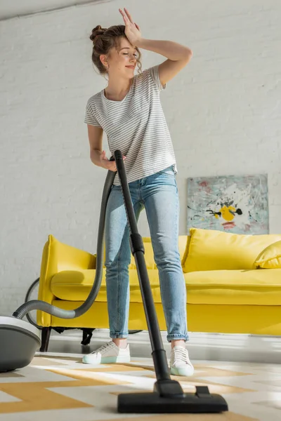 Selective focus of cheerful girl cleaning carpet with vacuum cleaner — Stock Photo