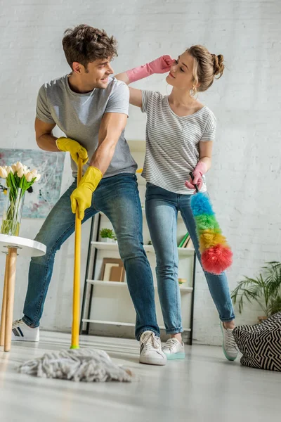 Foyer sélectif de gai fille et homme regardant les uns les autres tout en nettoyant dans le salon — Photo de stock