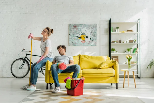 Hombre y mujer cansados sentados en un sofá cerca del hogar - foto de stock