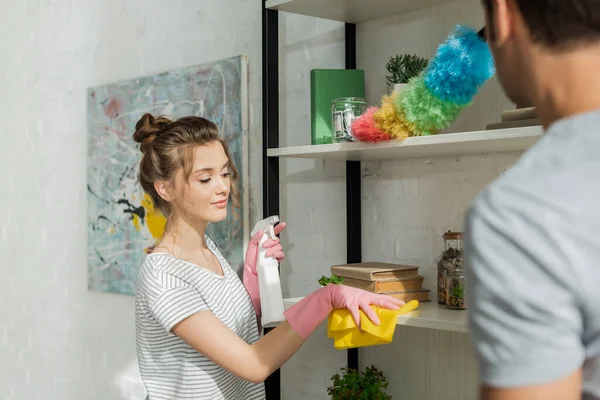 Selective focus of beautiful girl cleaning shelve near man — Stock Photo