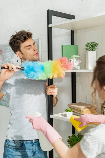 Selective focus of handsome man cleaning shelve near girl — Stock Photo