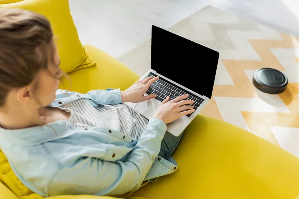 Selective focus of girl using laptop with blank screen while robotic vacuum cleaner washing carpet in living room — Stock Photo