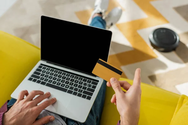 Top view of man online shopping while robotic vacuum cleaner washing carpet in living room — Stock Photo