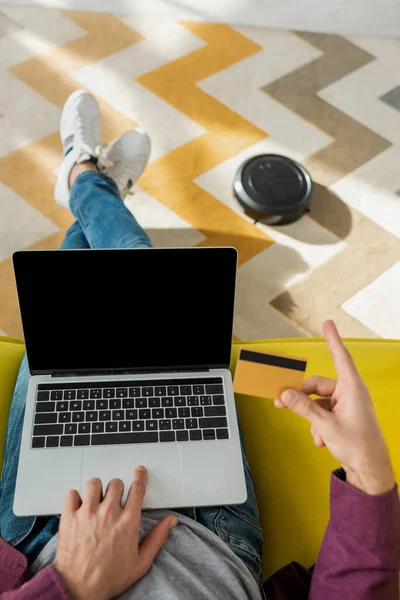 Abgeschnittene Ansicht des Mannes beim Online-Shopping, während Staubsaugerroboter Teppich im Wohnzimmer waschen — Stockfoto