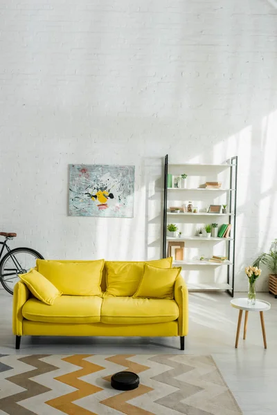 Роботизований пилосос пральний килим біля дивана в сучасній вітальні — стокове фото