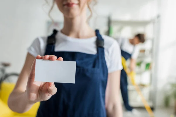 Cropped view of cleaner in uniform holding blank card — Stock Photo