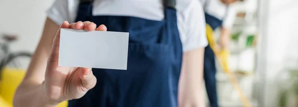 Plano panorámico de limpiador en uniforme con tarjeta en blanco - foto de stock