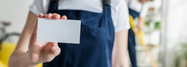 Colpo panoramico di pulitore in uniforme in possesso di carta bianca — Foto stock