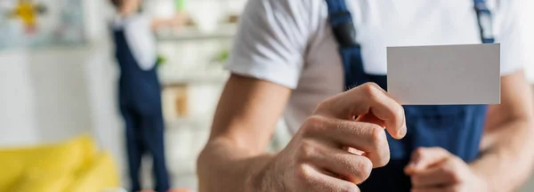 Панорамний знімок прибиральника в уніформі, що тримає порожню карту в квартирі — стокове фото