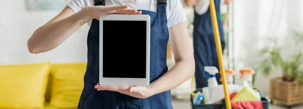 Prise de vue panoramique de nettoyant en uniforme tenant tablette numérique avec écran blanc — Photo de stock