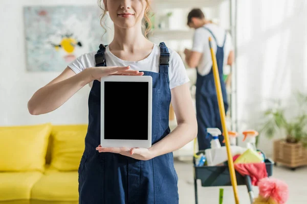 Vista recortada del limpiador sonriente que sostiene la tableta digital con pantalla en blanco - foto de stock