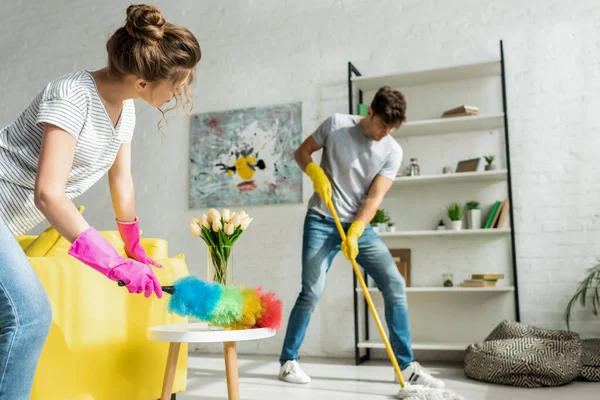 Enfoque selectivo del hombre y la mujer haciendo limpieza de primavera en el apartamento - foto de stock