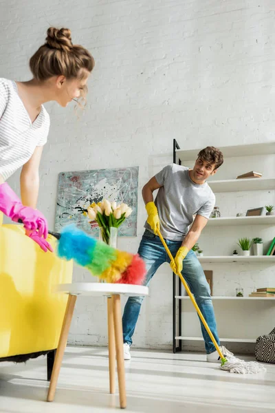 Selektiver Fokus von gutaussehenden Männern und jungen Frauen beim Frühjahrsputz in der Wohnung — Stockfoto