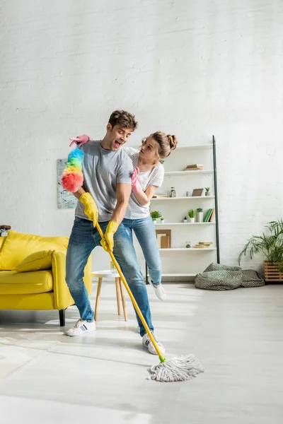 Feliz pareja haciendo limpieza de primavera en la sala de estar - foto de stock