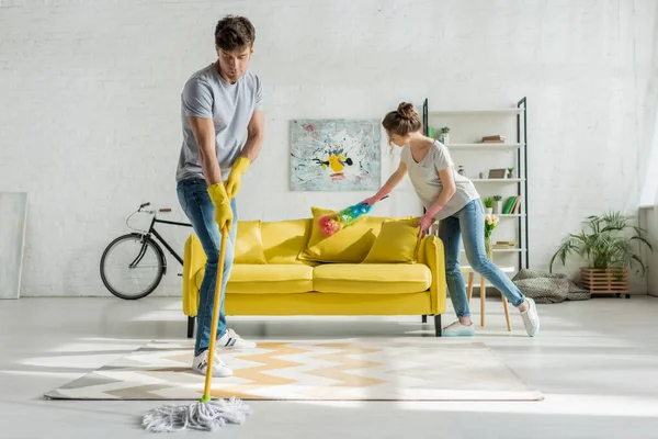 Hombre y mujer haciendo limpieza de primavera en la sala de estar - foto de stock