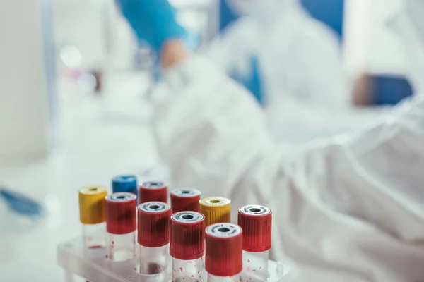 Foco seletivo de tubos de ensaio com amostras de sangue perto de bioquímicos em laboratório — Fotografia de Stock