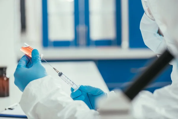 Enfoque selectivo del bioquímico que toma medicamentos del recipiente de vidrio con jeringa - foto de stock