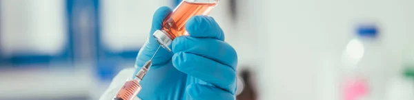 Ausgeschnittene Ansicht eines Biochemikers, der Medikamente aus einem Glasbehälter mit Spritze nimmt, Panoramaaufnahme — Stockfoto