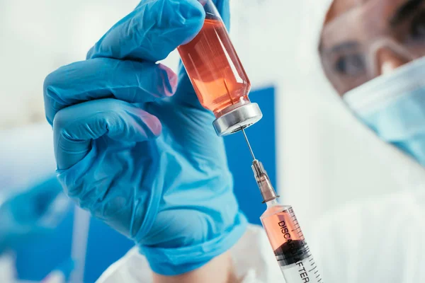 Selective focus of biochemist taking medicine with syringe from glass container — Stock Photo