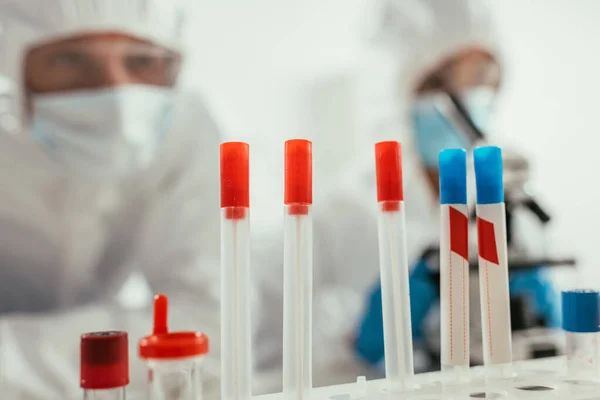 Selective focus of test tubes near biochemists in laboratory — Stock Photo