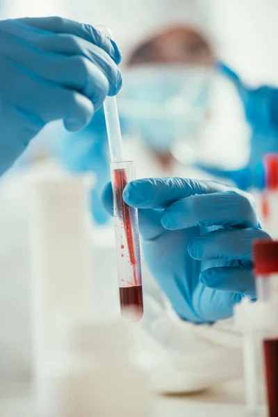 Cropped view of biochemist taking blood sample from test tube with pipette — Stock Photo