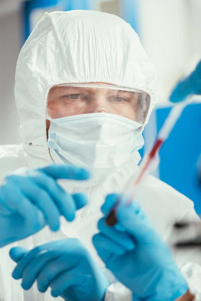 Visão parcial do bioquímico segurando pipeta e tubo de ensaio com amostra de sangue perto colega — Fotografia de Stock