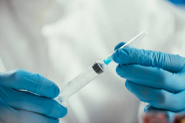 Cropped view of biochemist in rubber gloves holding syringe — Stock Photo