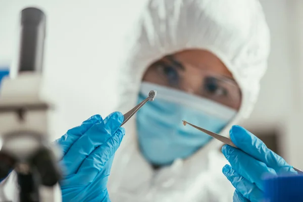 Foco seletivo do bioquímico segurando pequena pedra com pinças — Fotografia de Stock