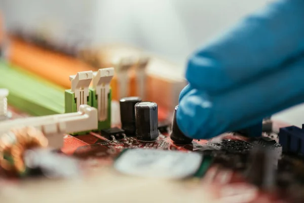 Enfoque selectivo de la mano del ingeniero en guante de goma cerca de la placa base de la computadora - foto de stock