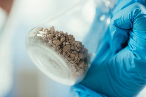 Vista de perto de pequenas pedras em frasco na mão em bioquímico — Fotografia de Stock