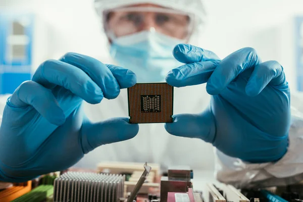 Selektiver Fokus des Ingenieurs, der Mikrochips in der Nähe von Computermotherboards hält — Stockfoto
