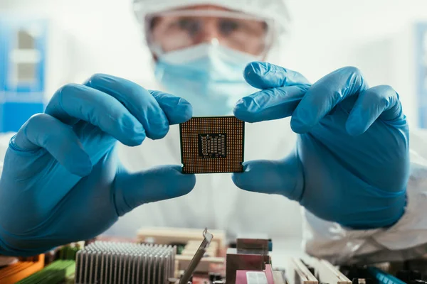 Enfoque selectivo del ingeniero que sostiene el microchip cerca de la placa base de la computadora - foto de stock