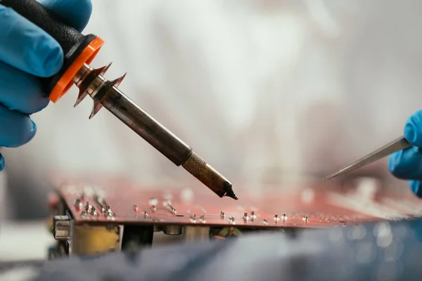 Cropped view of engineer holding soldering iron near computer motherboard — Stock Photo